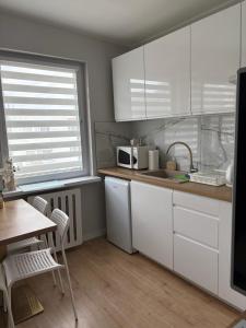 a kitchen with white cabinets and a table and a sink at Apartament Stare Miasto Malbork in Malbork