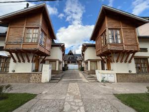 two wooden houses with a road between them at Apart Manantial del Valle in San Martín de los Andes