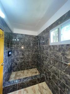 a bathroom with a large shower with black tiles at Cinnamon Cottage - Peaceful retreat in nature in Soufrière