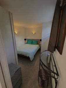 a small room with a bed and a glass table at GLAM in Saint-Jean-dʼArvey