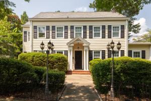 a white house with a gate and bushes at Sunny Efficiency In Historic Home in Durham
