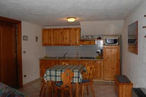 a kitchen with wooden cabinets and a table with chairs at Case Gran Paradiso Rhemes Saint Georges Vieux in Rhemes-Saint-Georges +6 photos
