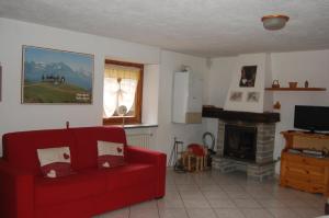 a living room with a red couch and a fireplace at Case Gran Paradiso Rhemes Saint Georges Vieux in Rhemes-Saint-Georges