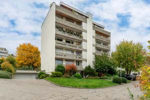 a tall white building with a yard in front of it at Swiss Suites Oberrohrdorf in Rohrdorf