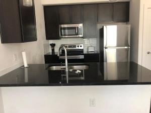 a kitchen with black cabinets and a stainless steel refrigerator at Modern Leander Getaway Near Shop- Leander TX in Leander