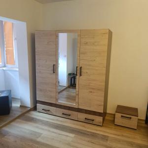 a wooden cabinet with a mirror in a room at Hunedoara Central Stay in Hunedoara