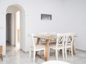 a dining room with a wooden table and white chairs at Casa Salmedina in Sanlúcar de Barrameda