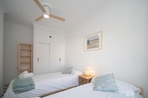 two beds in a room with white walls at Casa Salmedina in Sanlúcar de Barrameda