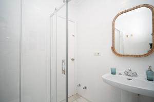 a white bathroom with a sink and a mirror at Casa Salmedina in Sanlúcar de Barrameda +34 photos