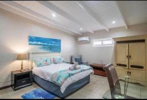 a bedroom with a bed and a table and a desk at House on the Beach in Glenashley in Durban