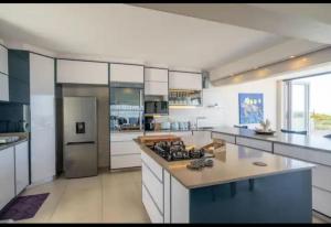 a large kitchen with white cabinets and a stove at House on the Beach in Glenashley in Durban