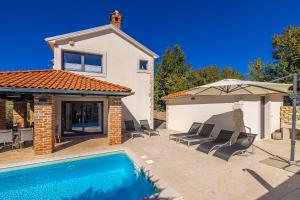 a house with a swimming pool and an umbrella at Villa Kvarner in Krk