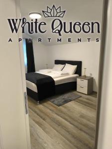 a bedroom with a bed and a sign that reads white auctionaments at White Quenn Apartments in Sanski most