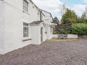 a white house with a table and chairs outside at Smithy Cottage at Bowland Bridge in Bowland Bridge