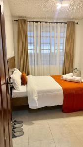 een slaapkamer met een bed met witte lakens en een oranje deken bij Nanyuki Luxe Stays 2 in Nanyuki