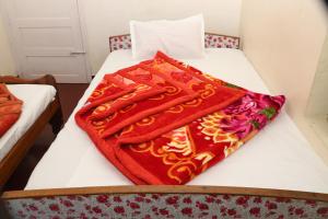 a red blanket sitting on top of a bed at GEE VEE Home Stay in Munnar
