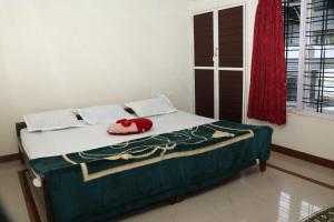 a bed in a room with a red pillow on it at GEE VEE Home Stay in Munnar
