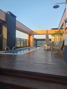 a wooden deck with chairs and a swimming pool at Ed Highline, piscina, lavanderia in Joinville