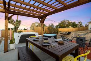 a wooden table on a patio with a wooden pergola at 3br 2bth, 10 Min To Jtnp, Ev Charger, Zen Garden in Joshua Tree