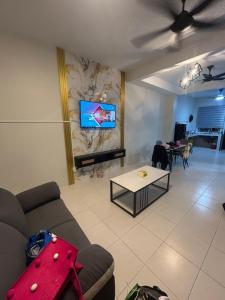 ein Wohnzimmer mit einem Sofa und einem Fernseher an der Wand in der Unterkunft Daus&iqah homestay jasin mlk in Merlimau