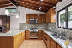 a kitchen with wooden cabinets and a sink at Bright Beach Stay, Balcony, Patio & Steps to Beach in Refugio