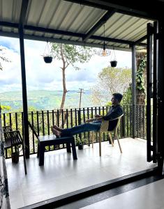 a man sitting in a chair on a porch at Orchid View Villa Mahabaleshwar 2 Bhk Villa in Mahabaleshwar