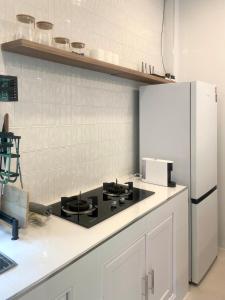 eine Küche mit schwarzem Herd und Kühlschrank in der Unterkunft The Whispering Palm Coconut Lane in Ko Phangan