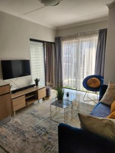 a living room with a couch and a flat screen tv at 1 Bed Crystal Lagoon Escape in Pretoria