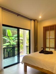 ein Schlafzimmer mit einem Bett und einer Glasschiebetür in der Unterkunft The Whispering Palm Coconut Lane in Ko Phangan