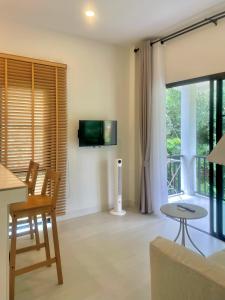 ein Wohnzimmer mit Fernseher und Tisch und Stühlen in der Unterkunft The Whispering Palm Coconut Lane in Ko Phangan