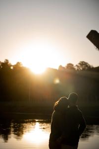 un homme et une femme debout devant un plan d'eau dans l'établissement Chácara Beija Flor com Casa de Campo charmosa pertinho de Curitiba, à Campo Magro