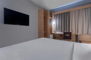 ein Hotelzimmer mit einem Bett und einem Flachbildfernseher in der Unterkunft Ibis Salvador Rio Vermelho in Salvador