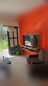 a living room with a flat screen tv and a chair at Casa Andar Térreo - Balneário Nordeste - Imbé - RS in Imbé