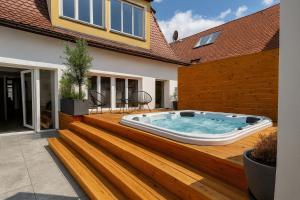 a hot tub on a wooden deck with a house at NAMASTÉ Homes - Luxus-Apartment mit Whirlpool & Garage in Bad Windsheim