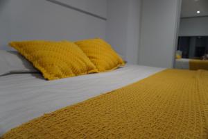 a bed with a yellow blanket on top of it at E1 Suites - Modern Comfort & Spa Luxury, Gibraltar in Gibraltar