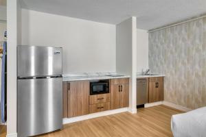 a kitchen with a stainless steel refrigerator and wooden cabinets at Baldwin Inn & Suites, SureStay Collection by Best Western in West Springfield +21 photos