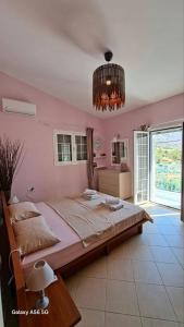 Una cama grande en una habitación rosa con una lámpara de araña. en Kineta Farmhouse, en Kineta