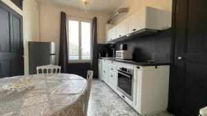 a kitchen with a table and a kitchen with white cabinets at Neyrpic Campus Université in Saint-Martin-dʼHères