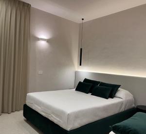 a bedroom with a white bed with black pillows at Angilè Rooms in Agrigento