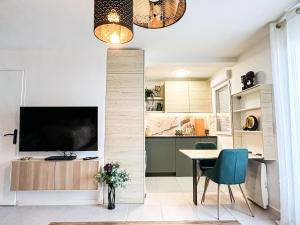 a living room with a television and a table and chairs at Studio Oasis Emeraude in Saulx-les-Chartreux