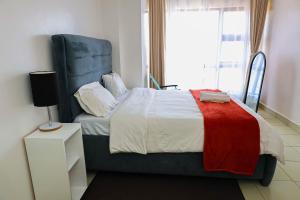 a bedroom with a bed with a blue headboard and a window at Luxe Loft Kinoo in Kikuyu