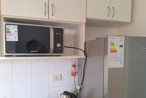 a microwave on a shelf above a refrigerator in a kitchen at Apartment 2 rooms downtown area with Balcony in Posadas +12 photos