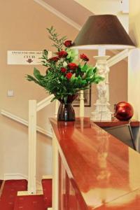 un jarrón de rosas sentado en una mesa con una lámpara en Villa Gold Poznań, en Poznan