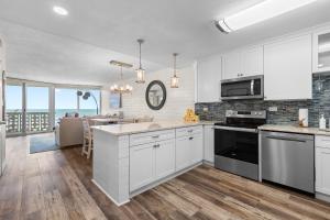 a kitchen with white cabinets and a dining room at Golden Arms 602 in New Smyrna Beach