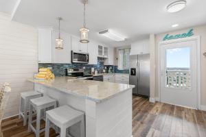 a kitchen with white cabinets and a counter with stools at Golden Arms 602 in New Smyrna Beach +23 photos
