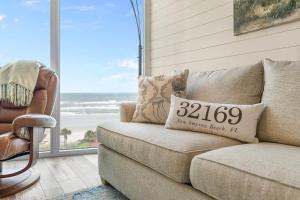 a couch in a living room with a beach view at Golden Arms 602 in New Smyrna Beach