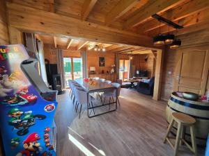 a dining room and living room with a table and a pinball machine at Le Chalet d'AxEllie Spa et Confort in Anould