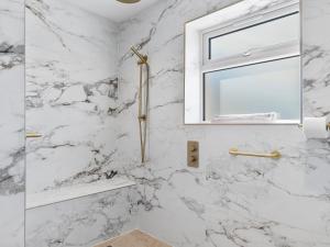 un bagno in marmo bianco con finestra e doccia di Newly Renovated Luxury Bungalow Pass the Keys a Ulverston Altre 28 foto