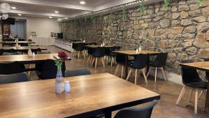 a restaurant with wooden tables and chairs and a stone wall at Hotel La Villa Mollendo in Mollendo