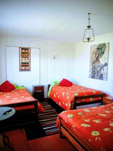 a bedroom with two beds with red sheets and a rug at Hospedaje Luna in Valdivia